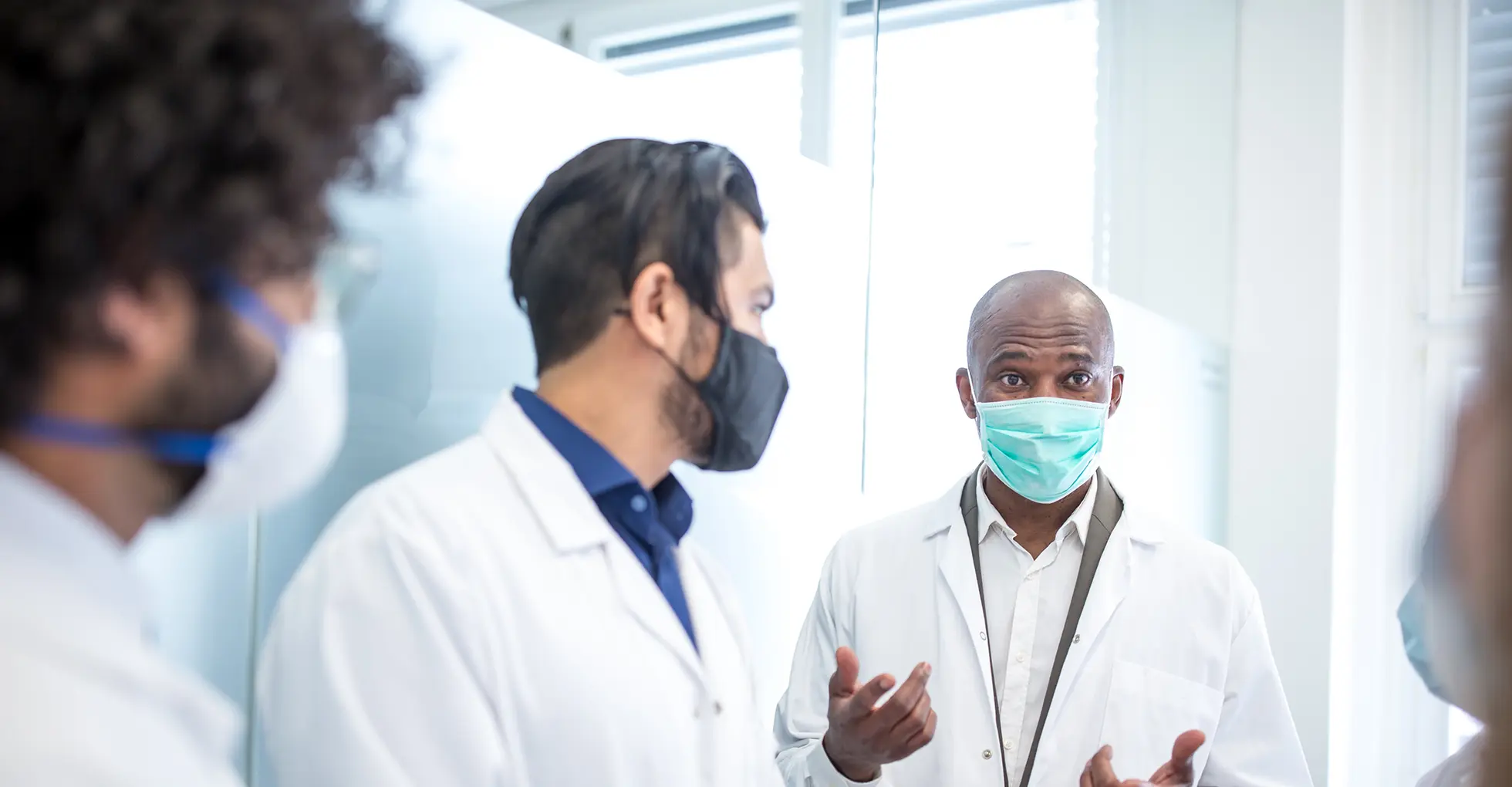 A picture of doctors at a healthcare institution wearing masks as they discuss.